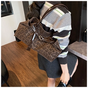 Detail of leopard print tote bag featuring glossy brown leather handles and metal hardware