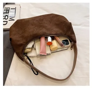 Macro shot of dark brown suede crescent bag showing spacious interior with daily items