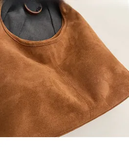 Gros plan détaillé du sac seau en daim marron montrant les coutures et la texture souple