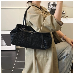 Detail of a chic black leopard print bowling bag styled with a professional trench coat