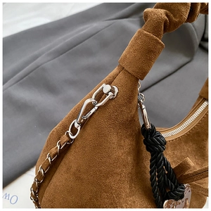 Detailed macro view of brown suede crescent bag with silver chain and heart charm