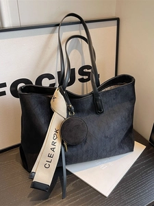 Black suede tote bag with geometric texture, long handles, and hanging round pouch