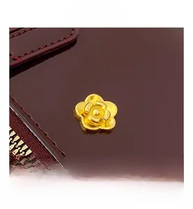 Macro shot of elegant burgundy leather bag featuring golden flower metal hardware and zipper