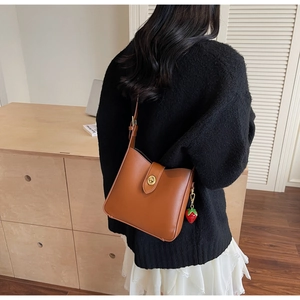 Detailed view of brown PU leather shoulder bag with gold twist lock and strawberry charm
