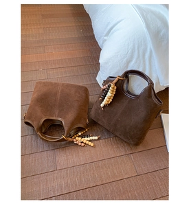 Détail de cabas vintage en daim avec poignées en cuir et perles décoratives en bois