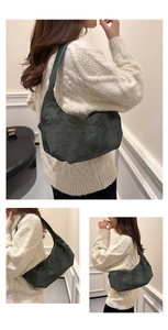 Detail of green suede dumpling bag featuring vintage pleats and a wide shoulder strap