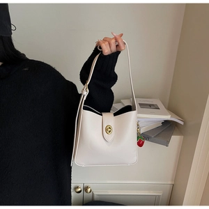 Detailed close-up of cream PU leather bucket bag with gold lock and strawberry charm