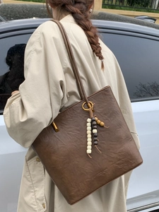 Retro deep brown oil wax leather tote bag with bead pendant on model outdoors