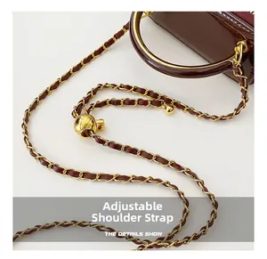 Macro shot of dark wine red leather bag featuring a gold chain strap with adjustable gold ball