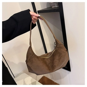 Close-up of a dark brown suede crescent-shaped shoulder bag with smooth zipper closure
