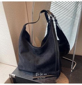 Détail du sac hobo en daim noir minimaliste avec bandoulière en cuir sur étagère