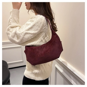 Close-up of a burgundy suede crescent hobo bag featuring fine stitching and soft texture