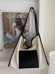 Contrast canvas tote bag with black faux leather trim shown hanging in a minimalist interior