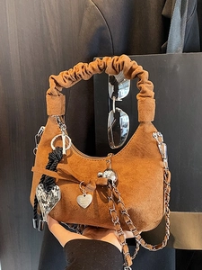 Caramel suede crescent bag with ruffled handle and heart pendant on a chain strap