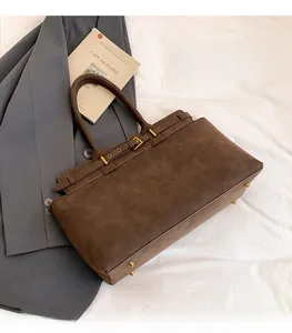 Detail of dark brown matte leather tote bag featuring gold buckle and protective base studs