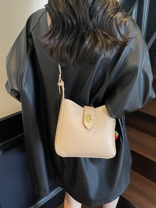 Chic beige bucket shoulder bag with gold twist lock and cute strawberry charm on a model
