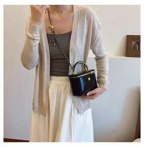 Detail of glossy black crossbody bag with gold camellia hardware and chain strap