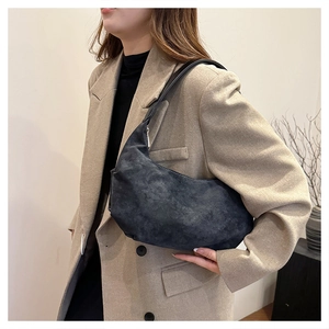 Detail view of dark grey suede crescent bag with matte finish and slim shoulder strap