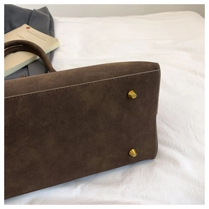 Detail view of smooth suede tote bag featuring reinforced seams and golden metal feet