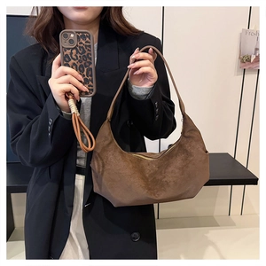 Detail view of a large brown suede hobo bag with a minimalist crescent dumpling shape