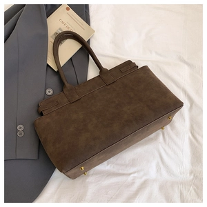 Detail of dark brown vintage tote bag showing sturdy handles and bottom protective studs