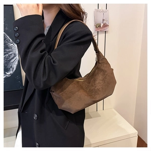 Brown suede dumpling bag detail showing premium crescent shape and zipper on shoulder