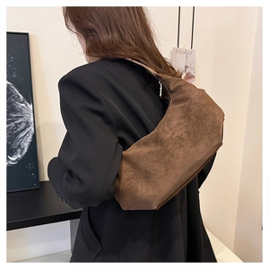 Brown suede crescent bag styled with a black blazer for a chic minimalist commuter look