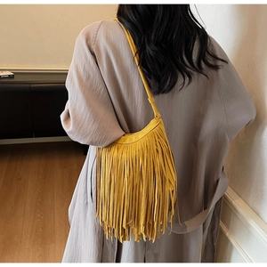 Detailed view of yellow suede hobo bag with long tassels on a female model