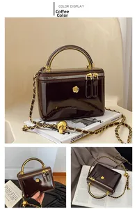 Close-up of coffee brown patent leather handbag with gold handle and petal logo detail