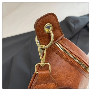 Detail of vintage brown textured crossbody bag with gold-tone hardware and stitching