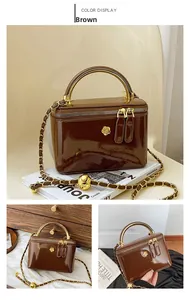 Detail of a brown patent leather box bag with gold flower buckle and chain strap