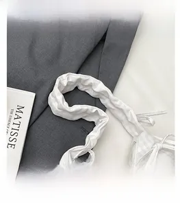 Detail of white checkered fabric handbag with pleated handle and ribbon bow decoration