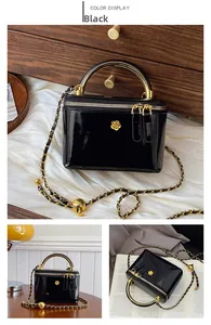 Detail of glossy black leather handbag with gold camellia accent and metal handle