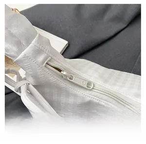 Close-up detail of smooth white nylon zipper and textured fabric on casual shoulder bag