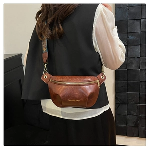 Detail of vintage brown leather waist bag with retro patterned strap and metal zipper