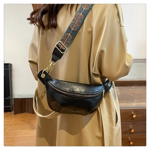 Detail of black leather crescent bag with ethnic geometric pattern wide strap on model