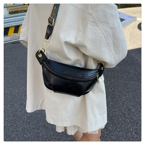 Detail of black pebbled leather crescent bag with colorful ethnic style woven strap
