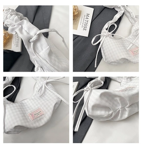 Detail of white plaid shoulder bag showing ruched handle and side ribbon bow decor