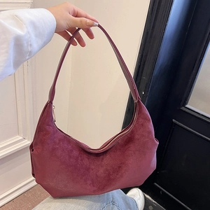 Minimalist burgundy dumpling hobo bag with matte texture shown in a hand-carried style