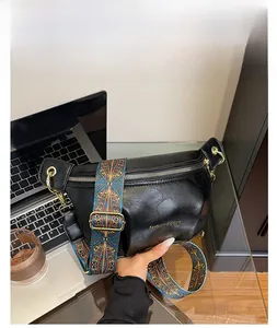 Detail of black faux leather crescent bag with colorful ethnic patterned shoulder strap