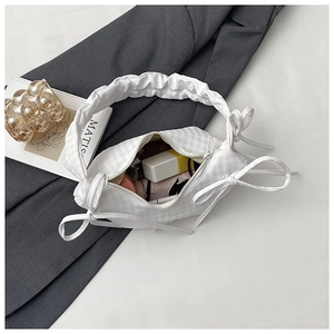 Macro shot of white checkered crossbody bag with bow ties showing interior storage