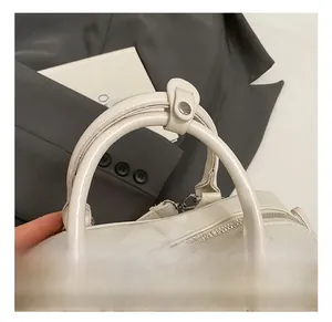Makroaufnahme der cremeweißen Griffe der Boston-Tasche mit Metallringen und Druckknopf
