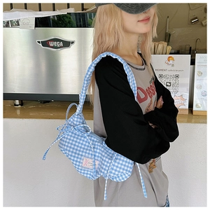 Detail of blue and white gingham knit shoulder bag with bow knot and pink woven label