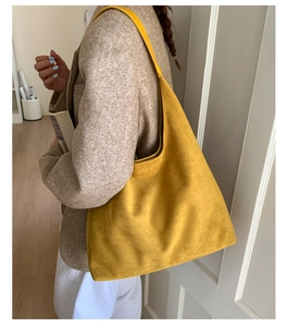 Vista lateral de un bolso tote amarillo mostaza mate con una chaqueta beige
