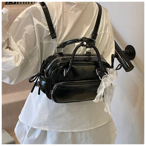 Details eines schwarzen glänzenden Rucksacks mit Schleifenanhänger und Multi-Taschen