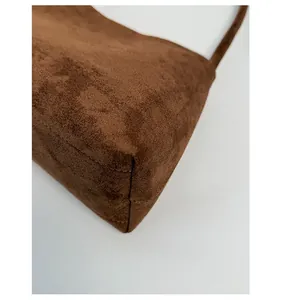 Detail of reinforced corner stitching on a brown suede shoulder bag for durability