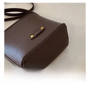 Dettaglio della pelle martellata marrone e del logo dorato sulla borsa a secchiello