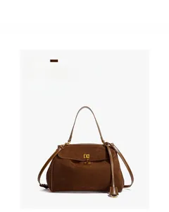 Détail du sac à bandoulière en daim marron foncé avec fermoir rotatif doré et poignée supérieure