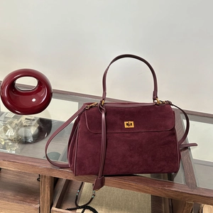 Détail du sac en daim bordeaux avec fermoir doré tournant et bandoulière réglable