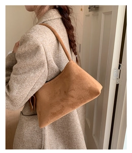 Close-up of caramel suede hobo bag worn by model in a stylish autumn outfit
